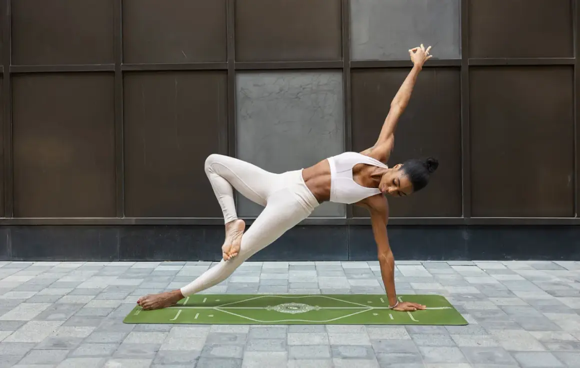 Mujer en posturas de equilibrio yoga, con una pierna levantada y el cuerpo girado, apoyada en una mano.