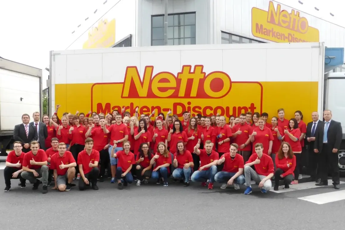 Gruppe von Mitarbeitern in roten T-Shirts vor einem Netto-LKW. Eine gute e-commerce ausbildung gehaltsperspektive für die Zukunft.