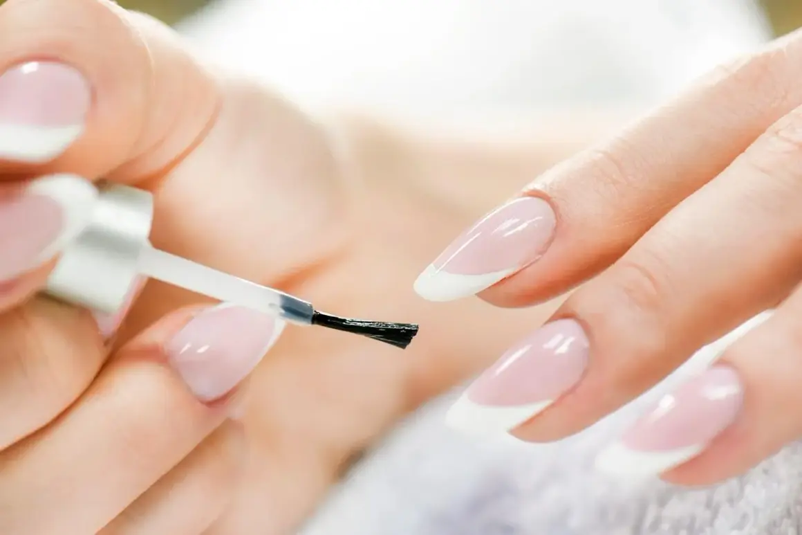 Mani curate che si preparano a fare unghie perfette con smalto trasparente.