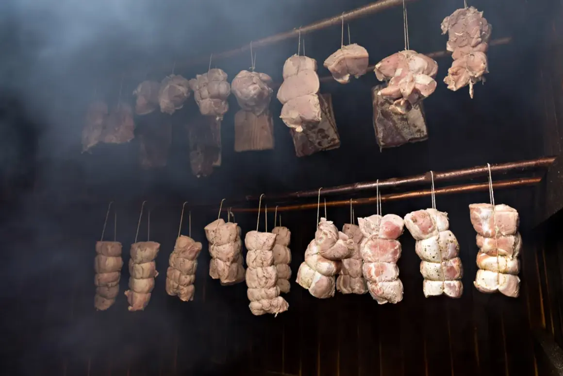 Mięsa zawieszone w dymie, gotowe do wędzenia na gorąco. Tradycyjny proces nadający smak i aromat.