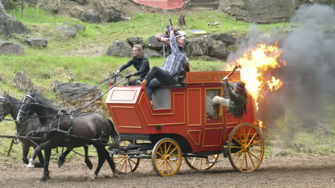Ein Wagen brennt bei einer Karl May Inszenierung in Elspe. Zwei Männer kämpfen, einer fällt aus dem brennenden Wagen.