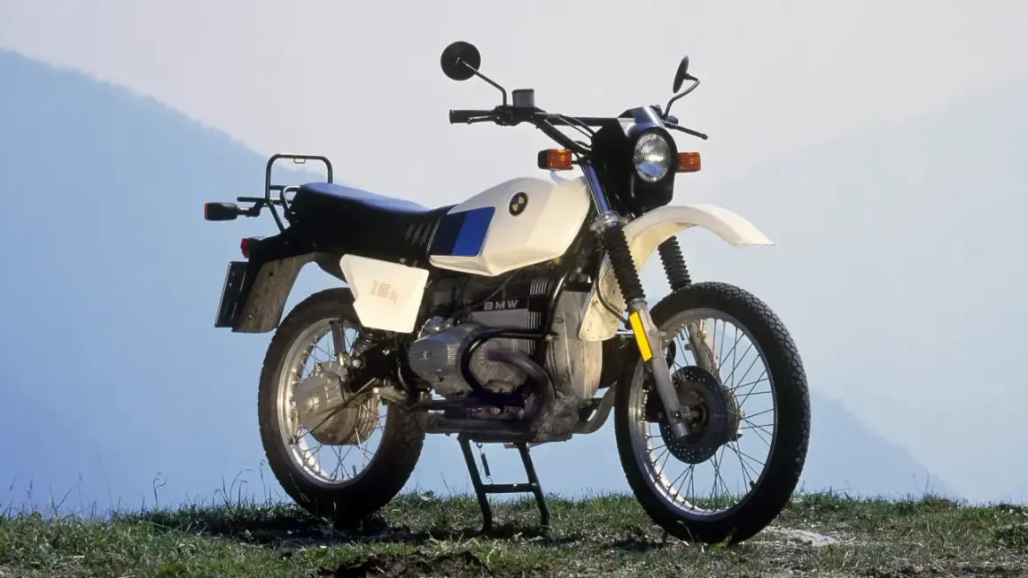 Una BMW R80GS, una icónica moto de los 80, lista para la aventura en un paisaje montañoso.