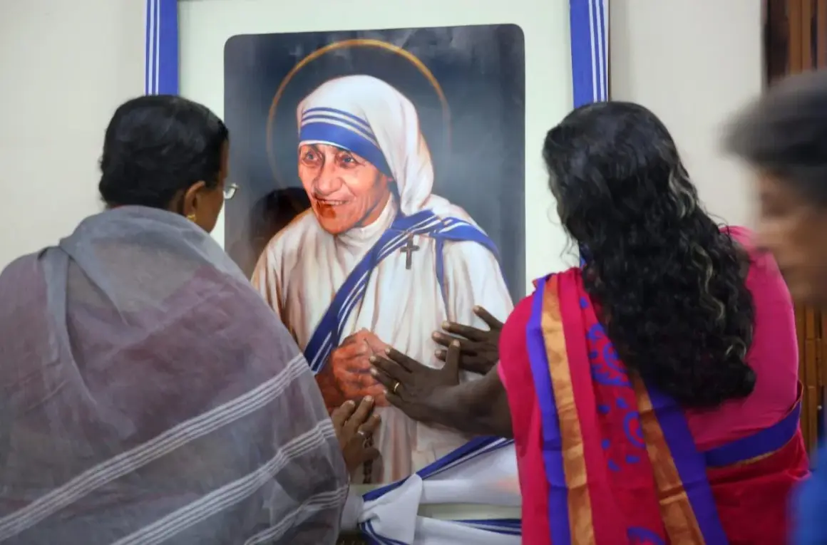 Frauen berühren ein Bild von Mutter Teresa, die ihr Leben den Armen widmete.