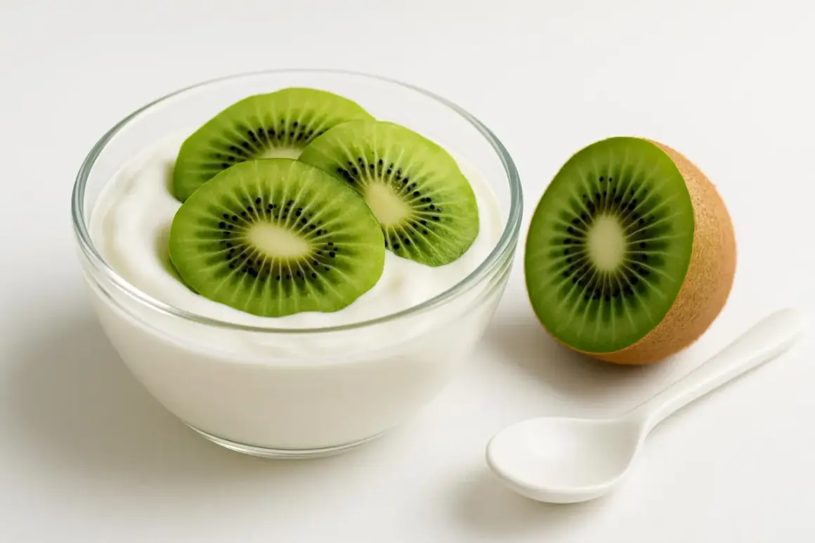 Yogurt con kiwi, un'ottima scelta tra gli alimenti che assorbono i gas intestinali. Una fetta di kiwi accanto a una ciotola di yogurt bianco con tre fette di kiwi sopra.