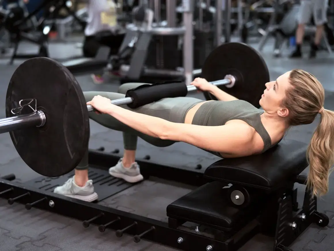 Kobieta wykonuje hip thrust z obciążeniem na ławce. Ćwiczenie to świetnie wzmacnia pośladki i jest możliwe do wykonania nawet w domu.