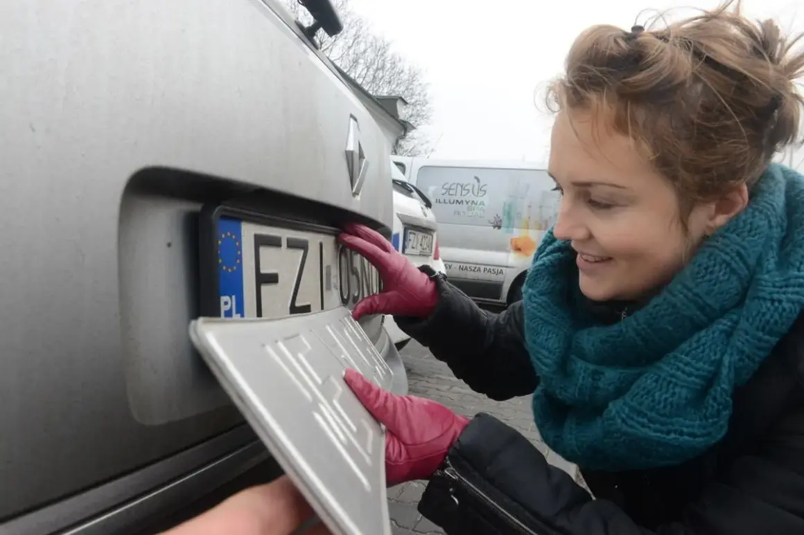 Kobieta w czerwonych rękawiczkach montuje tablicę rejestracyjną. To ważny etap rejestracji samochodu.