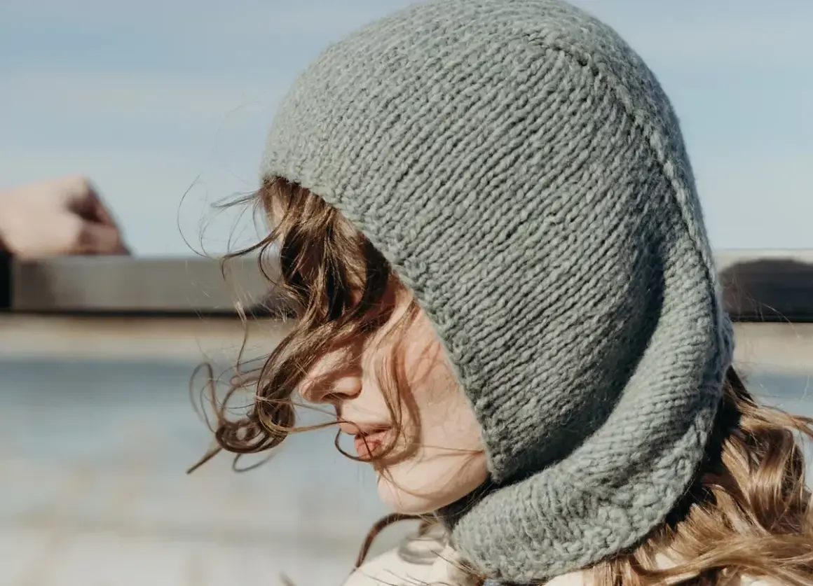 Una joven con un gorro tejido gris, que recuerda al balaclava origen, mira al horizonte.