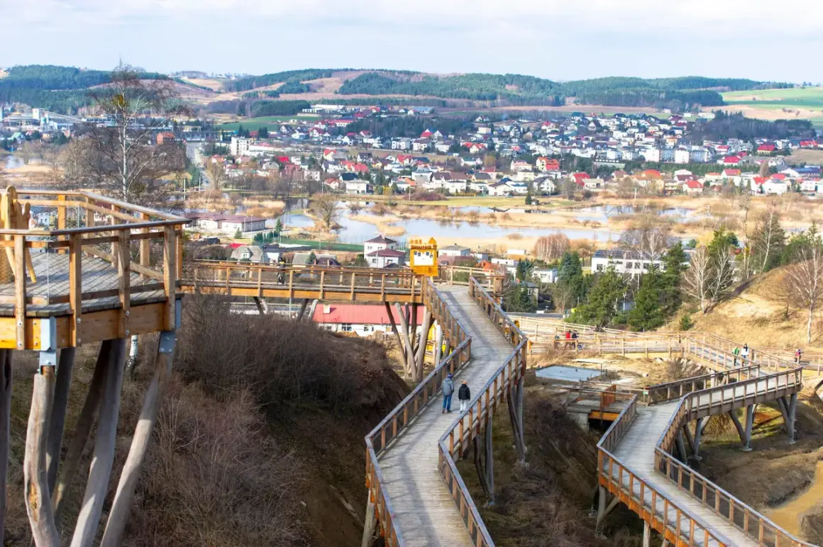 Drewniana wieża widokowa wije się wśród drzew, oferując panoramę miasteczka i jeziora.