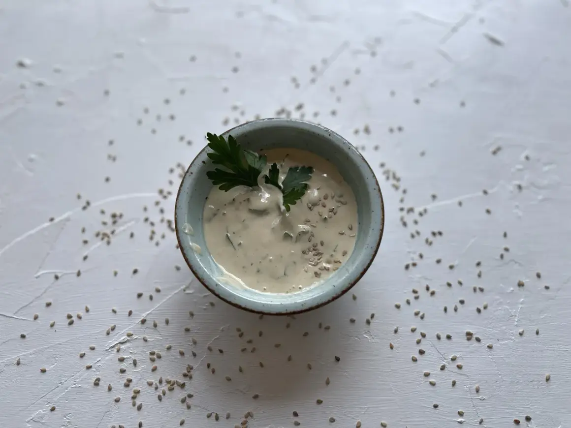 Cremige Sauce in einer Schale, garniert mit Petersilie und Sesam. Was ist Tahin? Eine köstliche Sesampaste, die hier als Dip serviert wird.