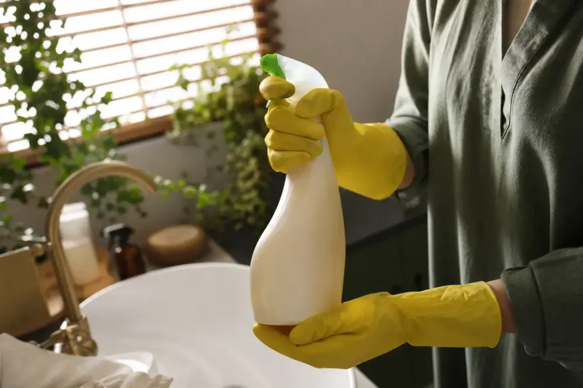 Gelbe Handschuhe halten eine Sprühflasche mit leicht vergilbtem Plastik.