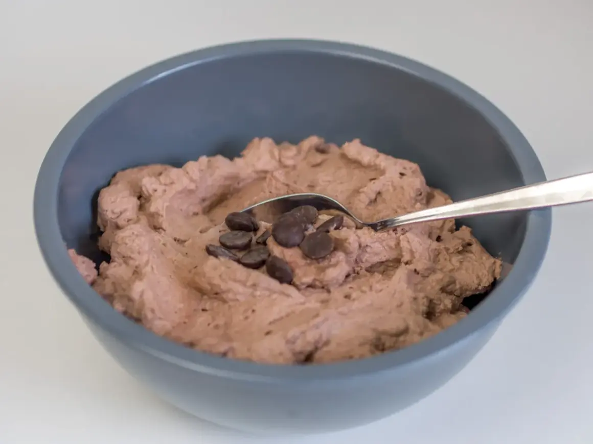 Schokoladige Sahnecreme mit Schokodrops in einer grauen Schüssel, bereit zum Genießen.