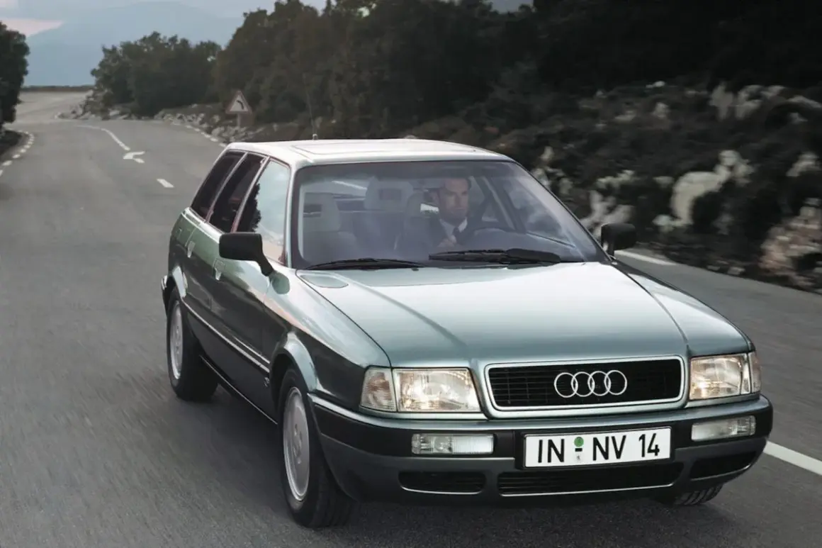 Mężczyzna w garniturze jedzie zielonym Audi 1.9 TDI po krętej drodze.