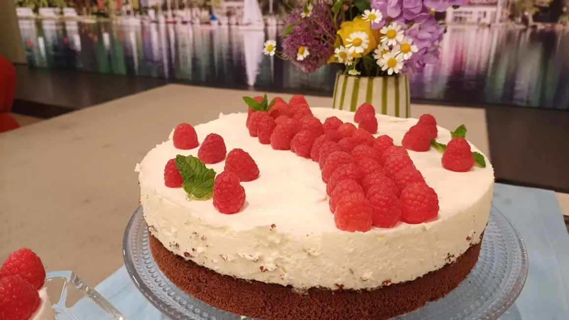 Himbeer Mascarpone Torte mit frischen Himbeeren und Minze verziert, ein Genuss für Augen und Gaumen.