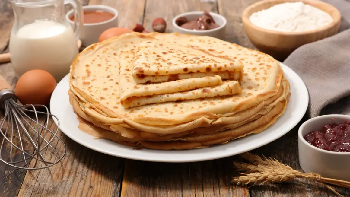 Una pila de crepes dorados, con ingredientes como leche, huevos y harina, evocan el origen de los crepes, un manjar sencillo y delicioso.
