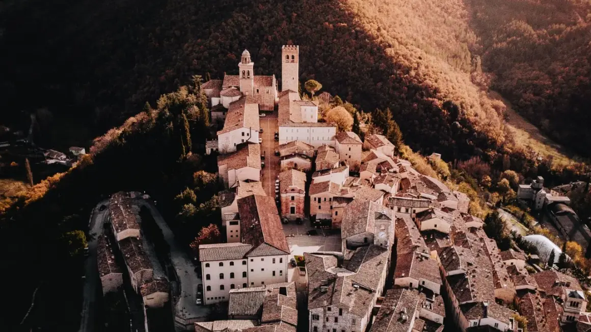 Borghi vicino Nocera Umbra, un gioiello medievale arroccato su una collina, con torri e tetti in terracotta immersi nel verde autunnale.