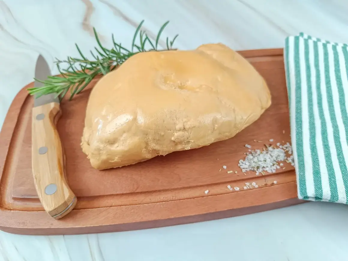 Un trozo de foie gras sobre tabla de madera, con romero, sal y un paño a rayas. La diferencia entre foie y foie gras es la preparación.
