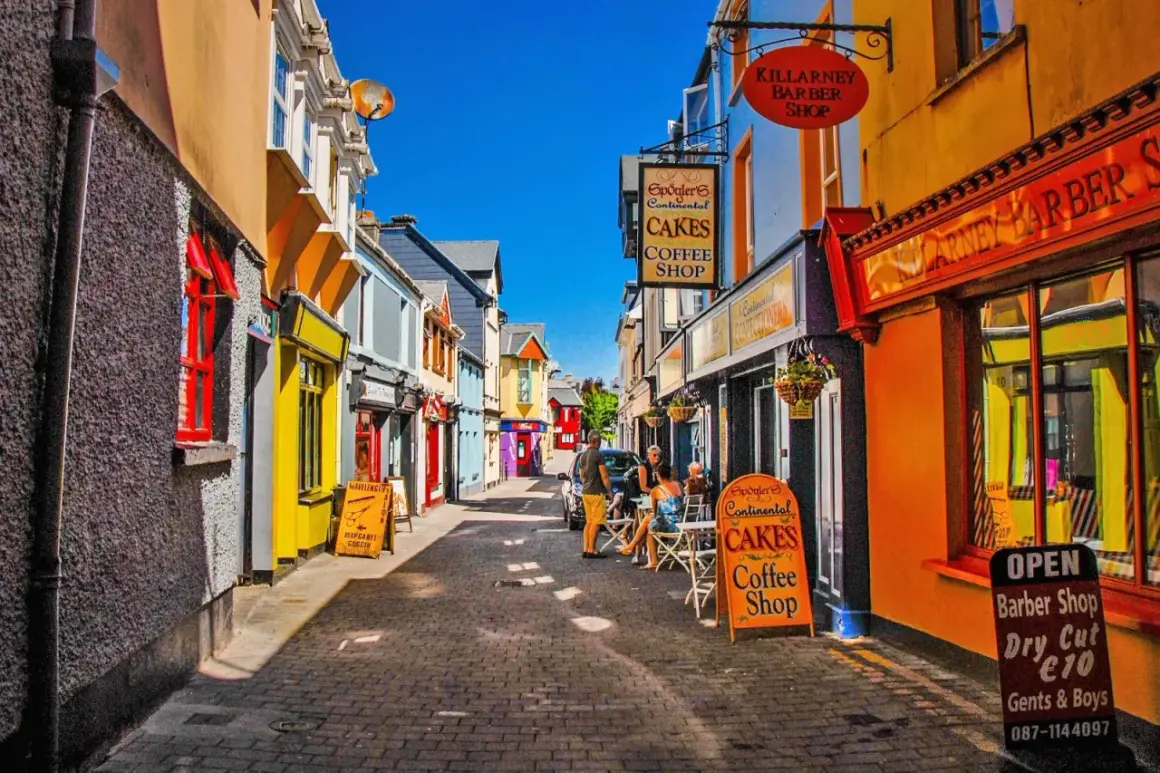 Färgglad gränd med butiker och caféer. En skylt för "Spögler's Continental Cakes Coffee Shop" syns tydligt, liksom en barberare. Kanske en trevlig plats att besöka efter en tur i Dublin.