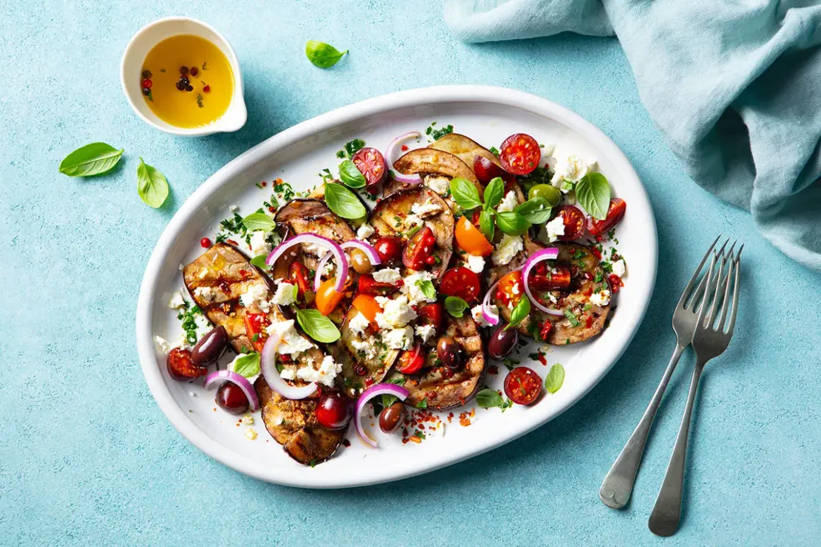 Gegrillte Auberginenscheiben mit Tomaten, Oliven, Feta und Basilikum – ein köstliches Beispiel für mediterrane Rezepte.