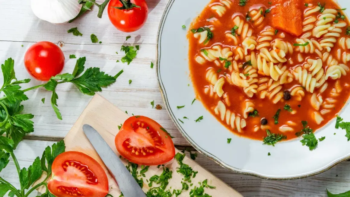 Aksamitna pomidorowa z rosołu z makaronem fusilli, świeżymi pomidorami i natką pietruszki.