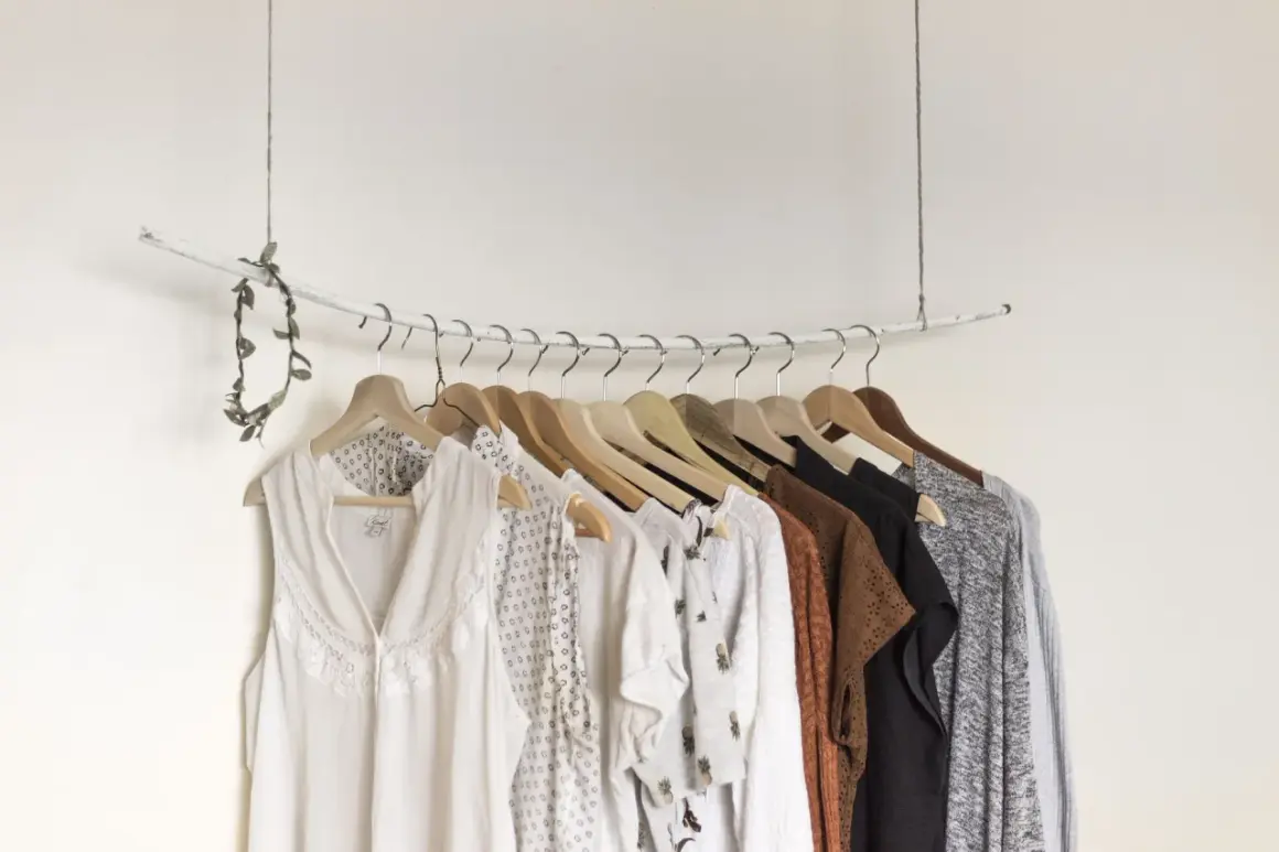 Eine Auswahl an Kleidungsstücken, die eine minimalistische capsule wardrobe bilden könnten, hängt an einer Garderobenstange.