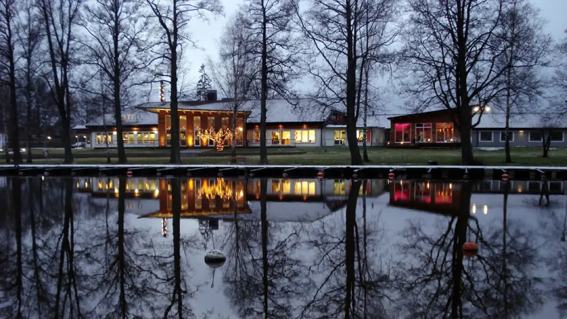 Vinterkväll vid Best Western Norra Vättern. Hotellets ljus speglas i vattnet, omgivet av kala träd.