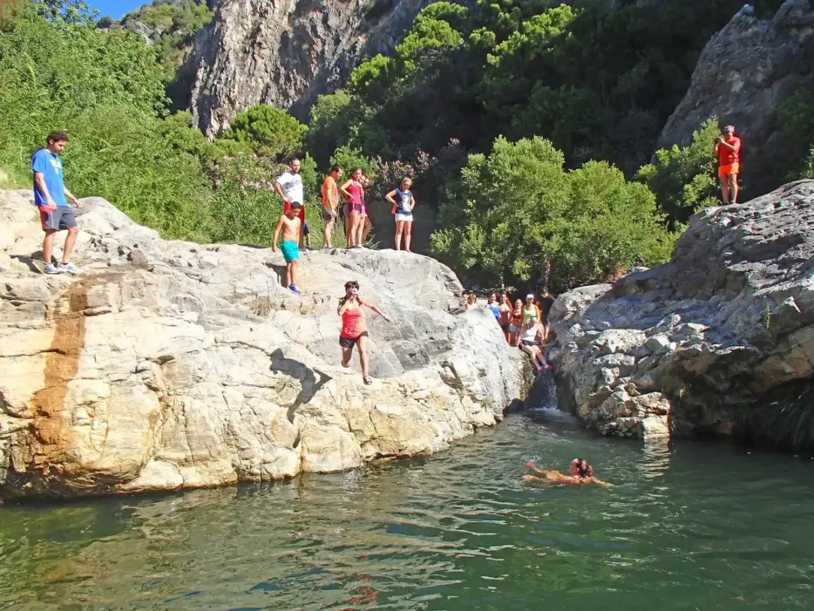 Gente salta a un río en la **Benahavís ruta río**. Un día soleado para disfrutar de la naturaleza y el agua.
