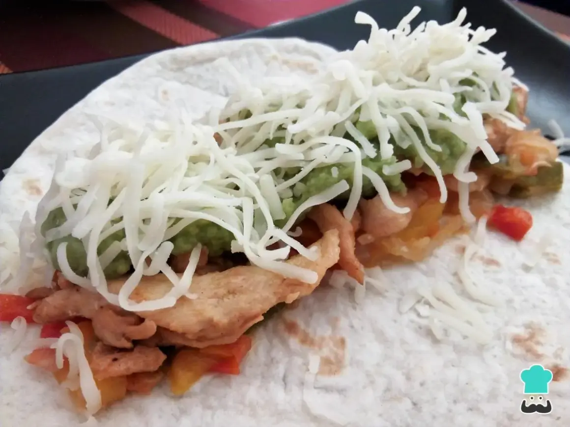 Fajitas de pollo y queso, con guacamole y pimientos salteados, envueltas en tortilla.