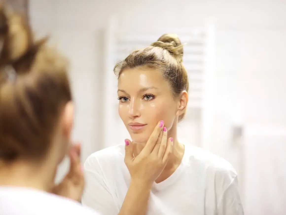 Donna si applica un siero sul viso, chiedendosi quanti sieri si possono usare insieme per una pelle luminosa.
