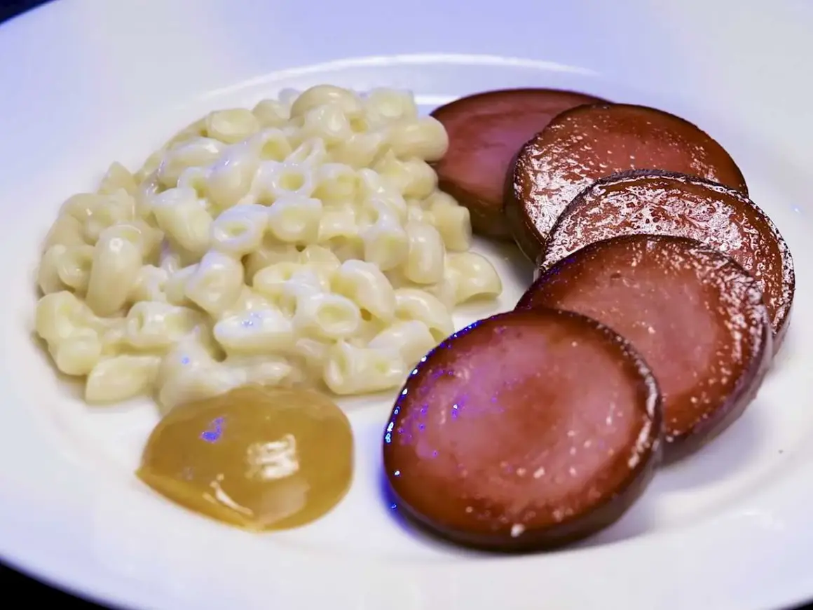 En tallrik med stuvade makaroner, skivad falukorv och en klick senap. En snabb och klassisk svensk måltid.