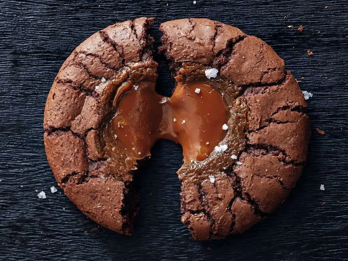 En brownie cookie med flytande karamell som rinner ut, strödd med havssalt.