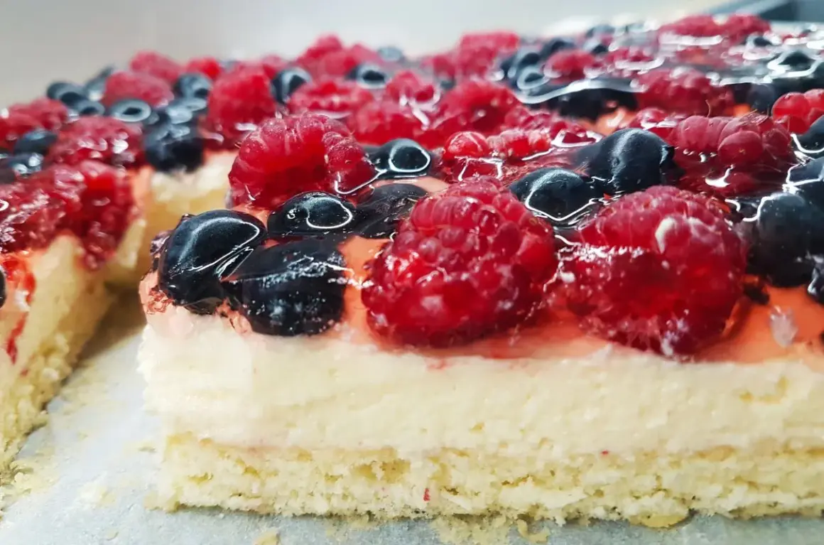 Pyszny biszkopt z galaretką bez kremu, obficie udekorowany malinami i borówkami. Idealny na letnie popołudnie.