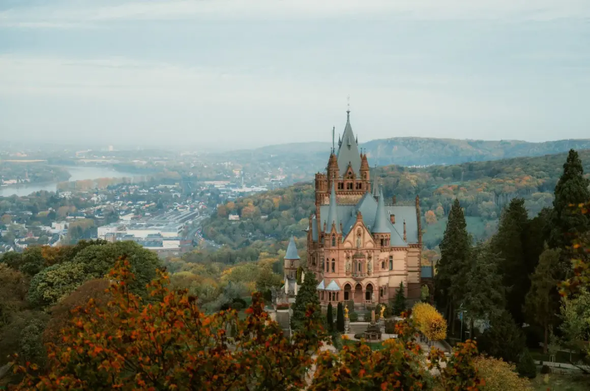 Märchenschloss im Herbstlicht, ein Juwel unter den Burgruinen NRW, thront über einer nebligen Stadt und einem Fluss.