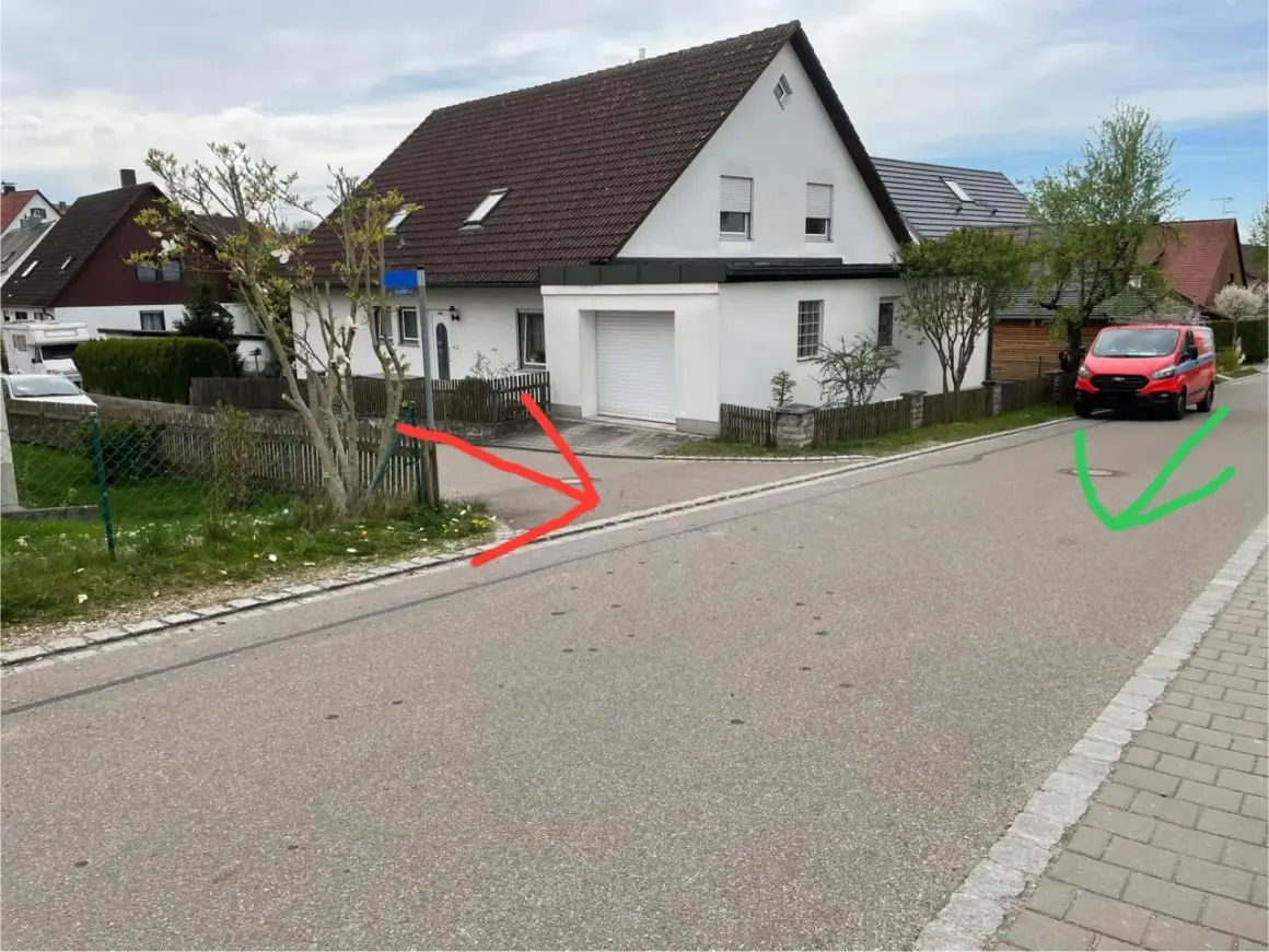 Ein roter Lieferwagen parkt auf der rechten Straßenseite, während rote Pfeile auf eine Einfahrt und ein grüner Pfeil auf einen Gullydeckel zeigen. Das Schild "rechts vor links" ist nicht sichtbar.