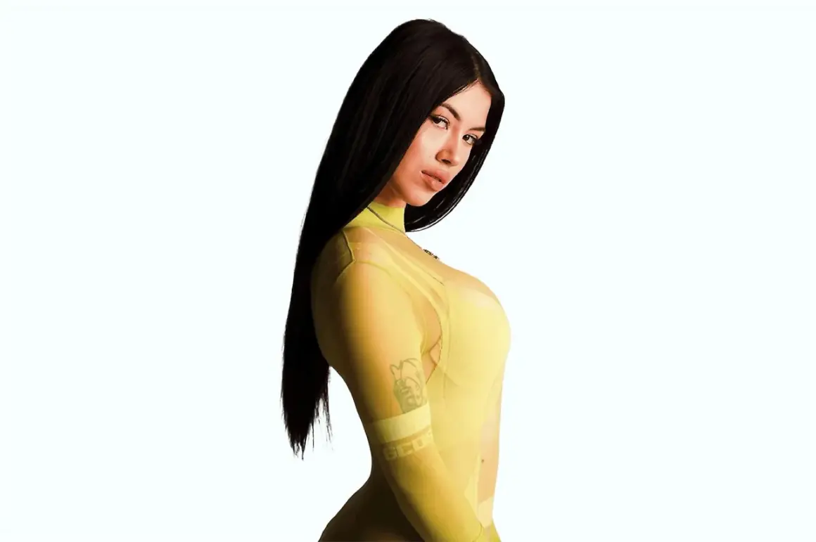 Anna, la cantante, posa con un abito giallo trasparente, mostrando un tatuaggio sul braccio.