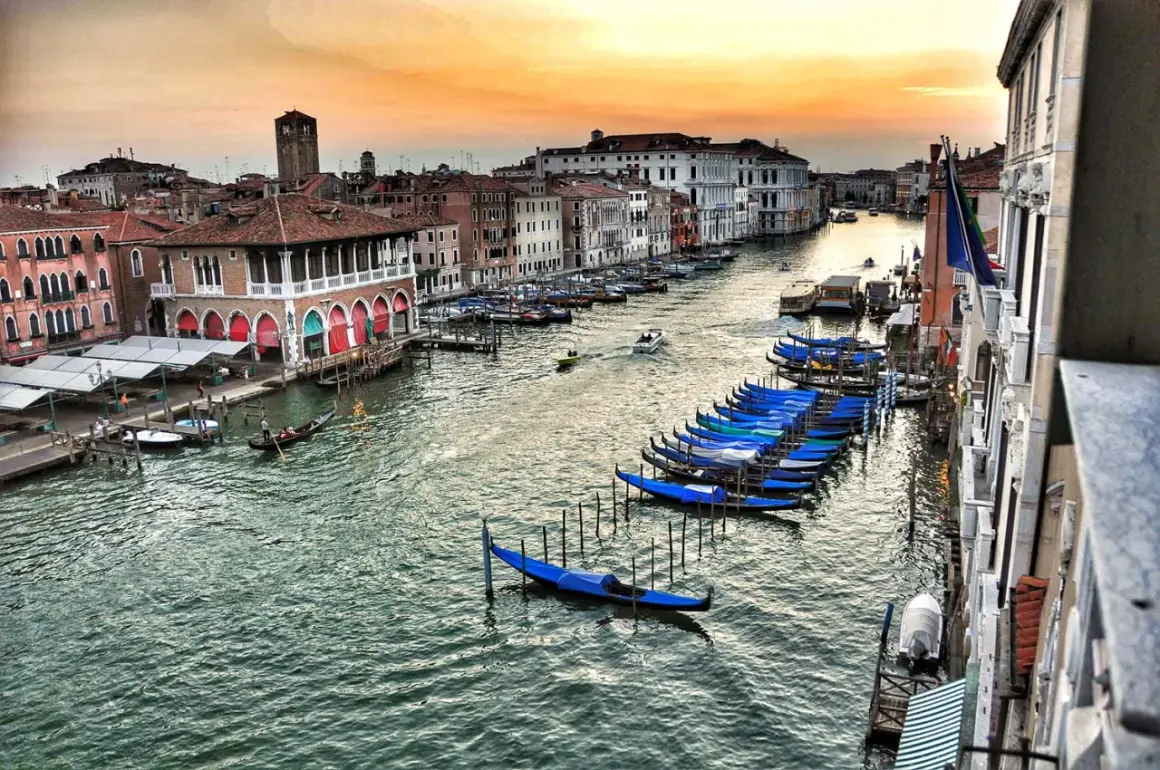 Wenecja co zobaczyć w 1 dzień: gondole czekają nad Canal Grande, a zachodzące słońce maluje niebo.
