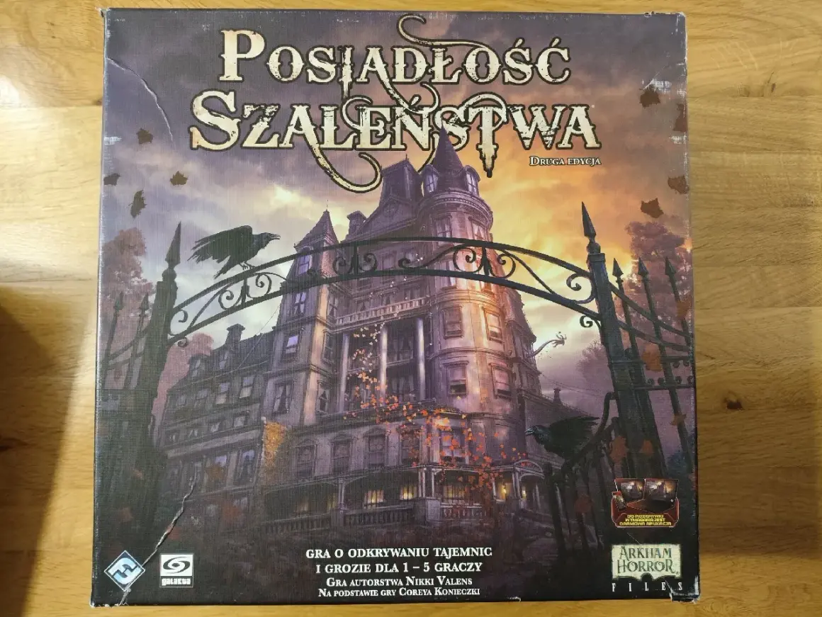 Okładka gry planszowej "Posiadłość Szaleństwa" z mroczną posiadłością i wronami. Scenariusze tej gry przeniosą Cię w świat tajemnic i grozy.