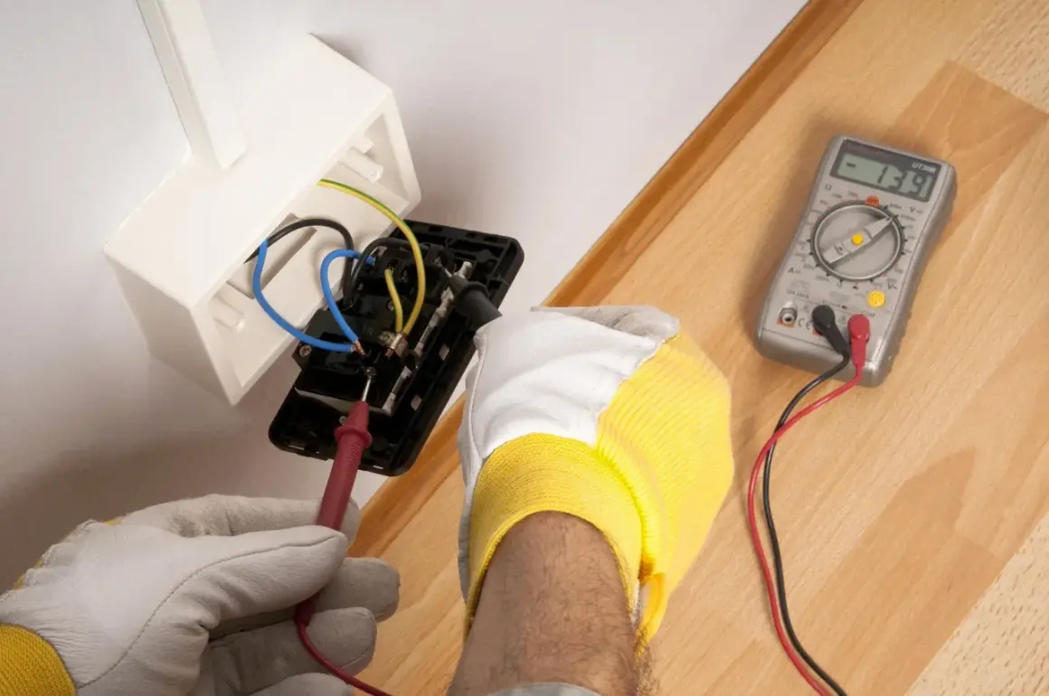 Elektryk sprawdza napięcie w gniazdku. Woltomierz służy do pomiaru napięcia elektrycznego, co jest kluczowe przy pracach instalacyjnych.