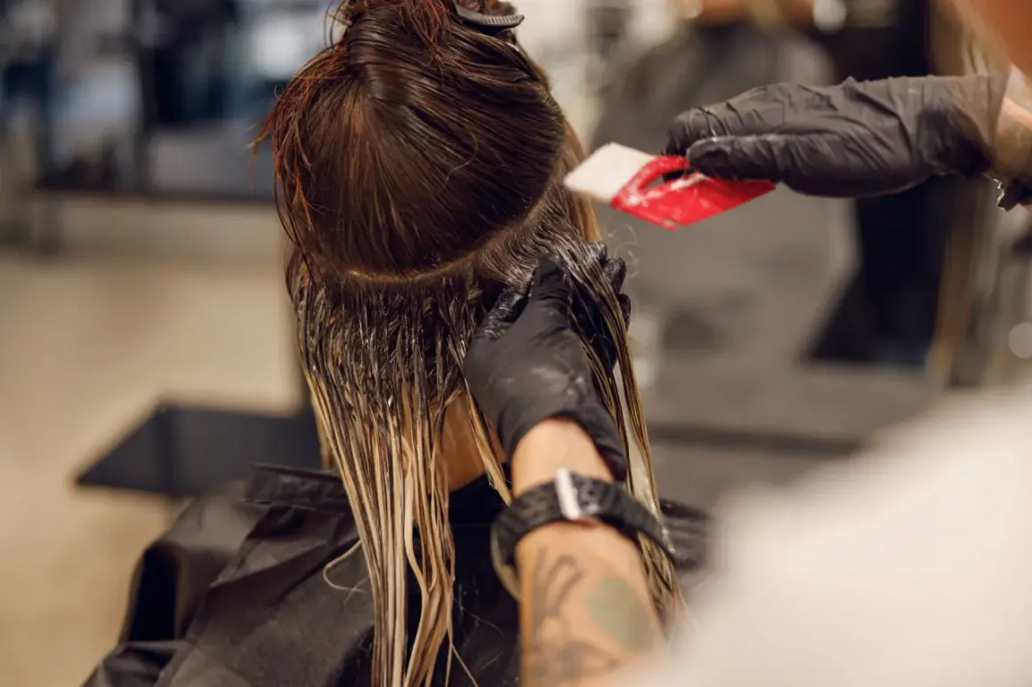 Friseur trägt Farbe auf, um einen sanften Farbverlauf zu erzielen. Die color melting Technik lässt die Töne harmonisch ineinander übergehen.