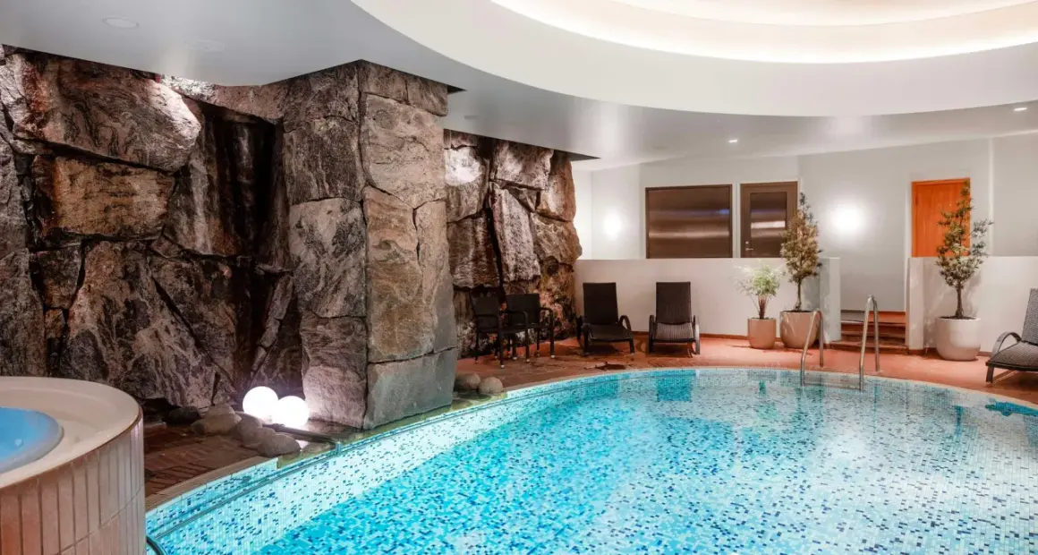 Avslappnande poolområde med stenformationer och bubbelpool, perfekt för en paus efter en dag som viking på ett hotell i Stockholm.
