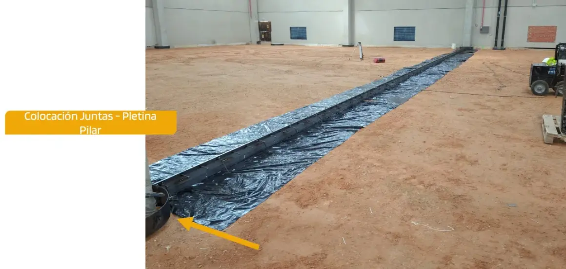 Instalación de una solera de hormigón con armadura metálica sobre plástico negro en interior de nave.
