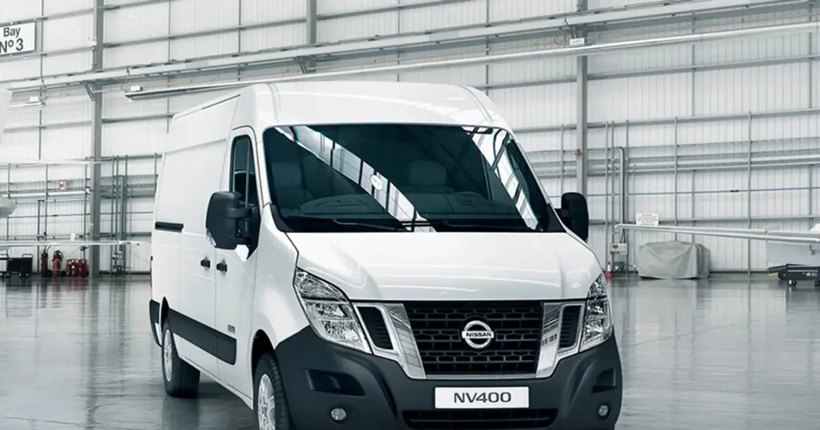 Biały van Nissan NV400 stoi w przestronnym magazynie.