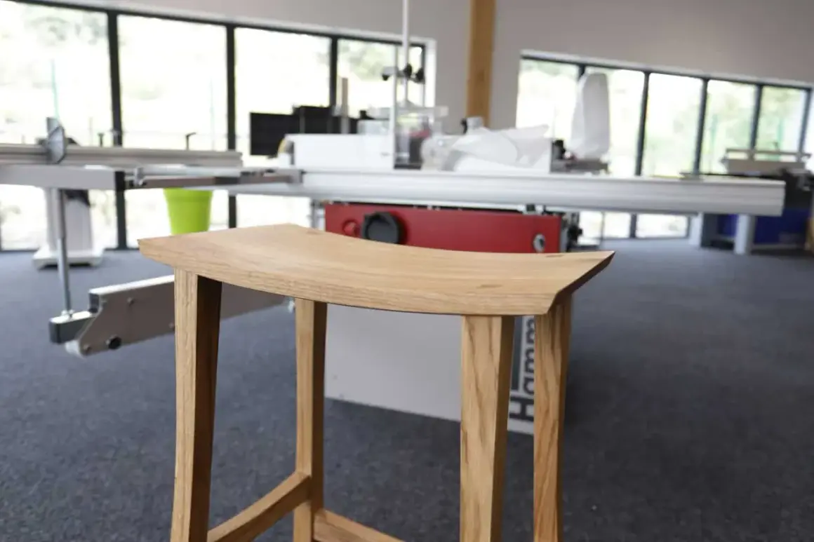 Tabouret en bois, œuvre d'un artisan utilisant un combiné bois Hammer. Lignes épurées, bois naturel.