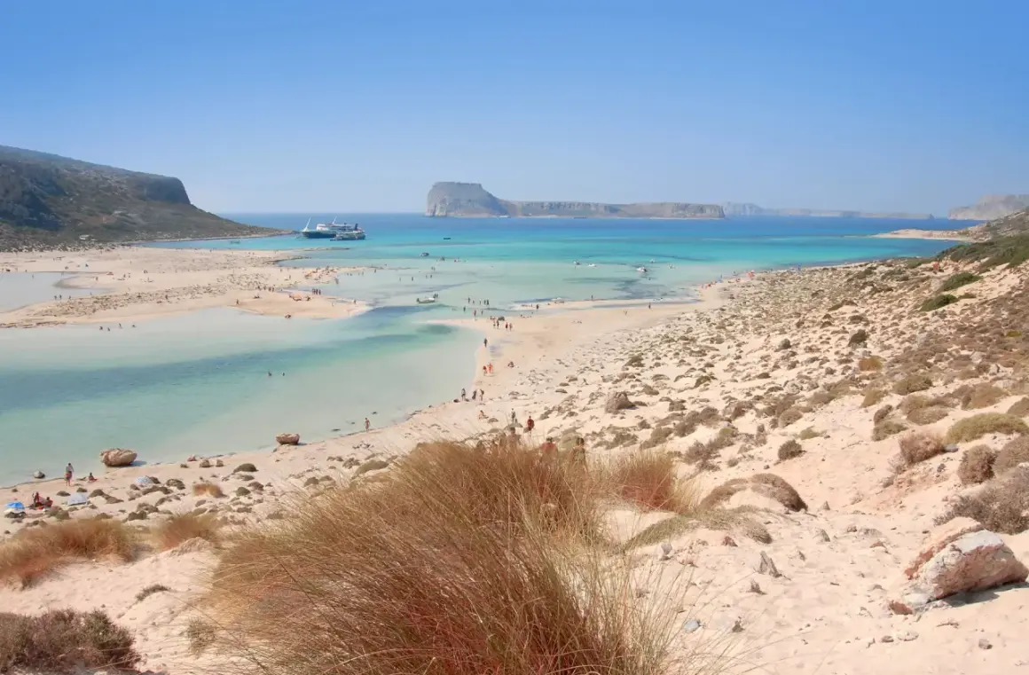 Piękne plaże na Krecie, Chania. Turkusowa woda, piaszczyste wybrzeże i góry w tle.