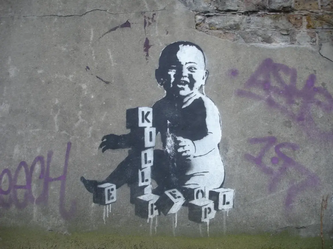 Dziecko bawi się klockami z literami, tworząc napis "KILL". To mocne co to jest graffiti, które prowokuje do myślenia.