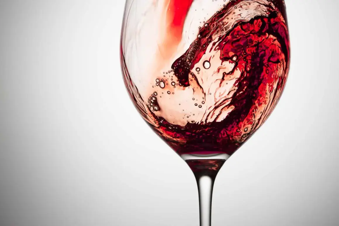 Vortice di vino rosso in un calice, con bollicine che rivelano la presenza dei tannini, responsabili della sensazione di astringenza.