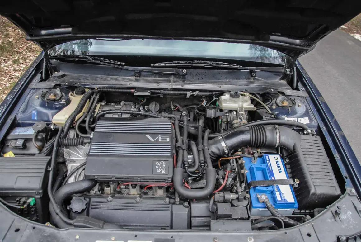 Silnik V6 wolnossący Peugeot, z widocznym akumulatorem Varta i elementami układu dolotowego.