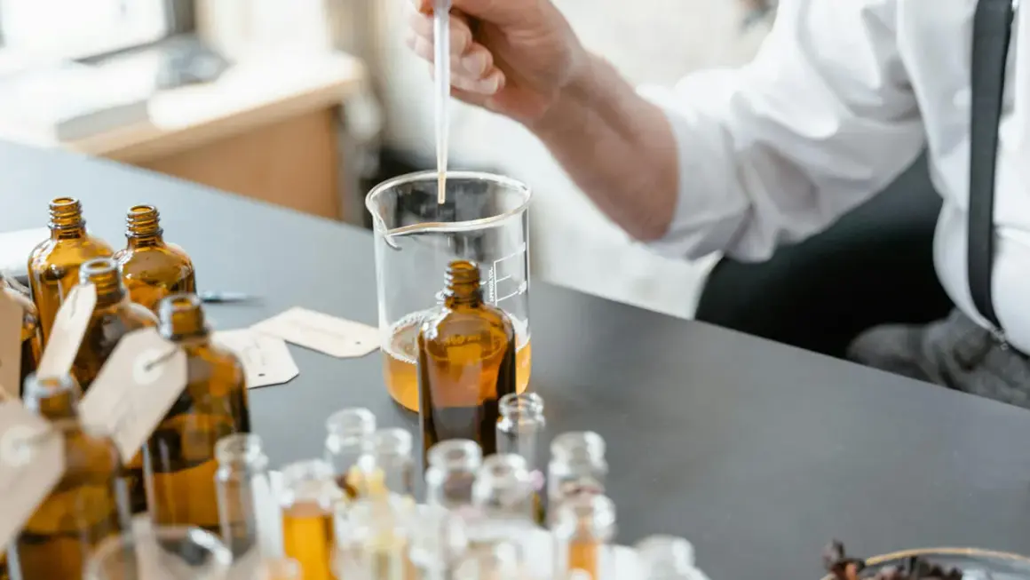 Ricerca su coumarin cos'è: un profumiere testa essenze in ambrate bottigliette, con un contagocce in un becher.