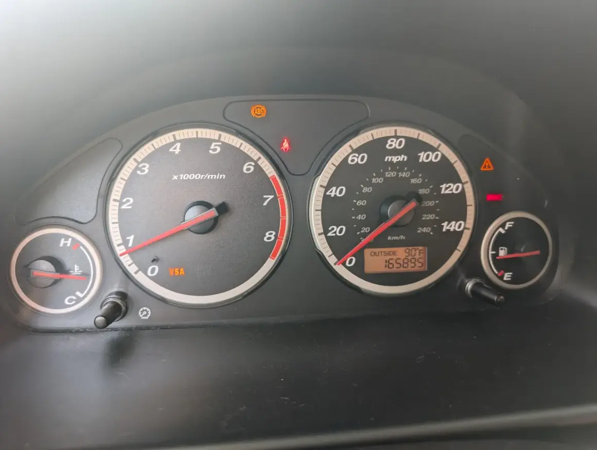 Kontrolki na desce rozdzielczej Hondy CR-V: świeci się kontrolka VSA, ABS, hamulców. Temperatura zewnętrzna 90°F, przebieg 165895.