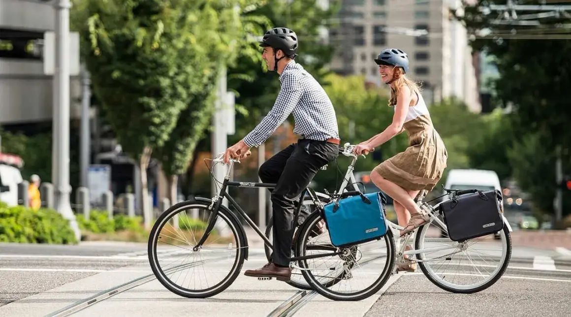 Ein Paar radelt mit Gepäcktaschen durch die Stadt. Perfekt für eine ADFC Fahrradtour, die Liste der Ausrüstung ist komplett.