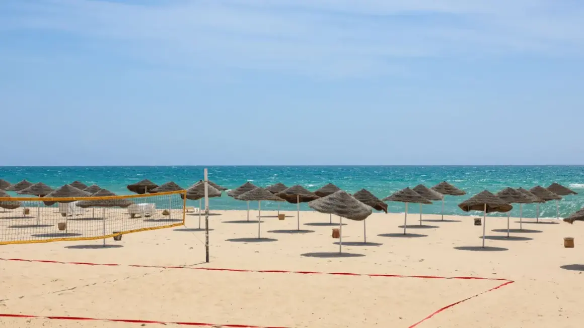 Piękna plaża w Tunezji we wrześniu. Słoneczna pogoda, turkusowe morze i rzędy parasoli zapraszają do relaksu.